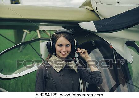 Stock Photo - Caucasian woman wearing a headset near airplane. Fotosearch