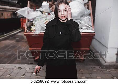 Caucasian woman wearing black coat smoking cigarette near dumpster View Large Photo Image Stock Image - Caucasian woman wearing black coat smoking cigarette near dumpster. Fotosearch