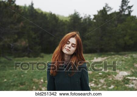 Stock Image - Caucasian woman wearing coat in field. Fotosearch