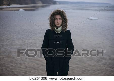 Stock Photograph - Caucasian woman wearing coat near ocean. Fotosearch