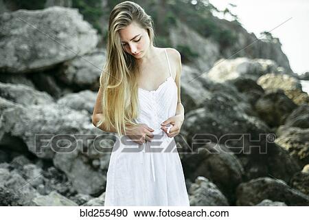 Caucasian woman wearing dress standing on the rocks View Large Photo Image Stock Image - Caucasian woman wearing dress standing on the rocks. Fotosearch