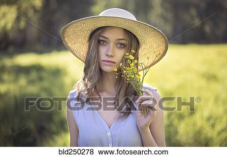 Caucasian woman wearing hat holding wildflowers View Large Photo Image Stock Photo - Caucasian woman wearing hat holding wildflowers. Fotosearch