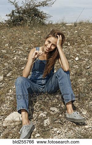 Caucasian woman wearing overalls sitting in rocky field View Large Photo Image Stock Photograph - Caucasian woman wearing overalls sitting in rocky field. Fotosearch