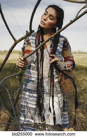Stock Image - Caucasian woman wearing traditional clothing holding branch. Fotosearch