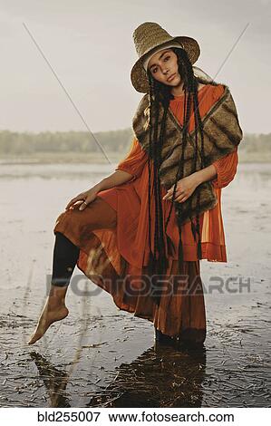 Stock Photo - Caucasian woman wearing traditional clothing wading in water. Fotosearch