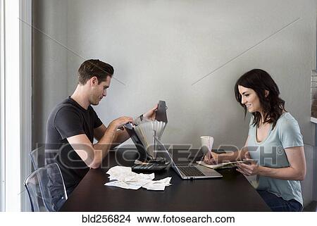 Caucasian woman writing notes near laptop while man searches files View Large Photo Image Picture - Caucasian woman writing notes near laptop while man searches files. Fotosearch