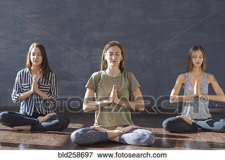 Stock Photo - Caucasian women meditating in yoga class. Fotosearch