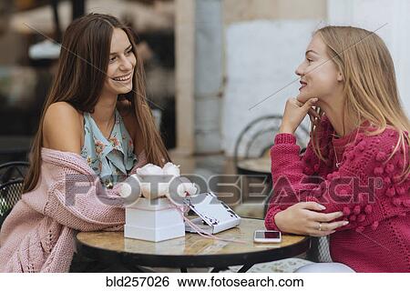 Stock Photograph - Caucasian women sitting at table. Fotosearch