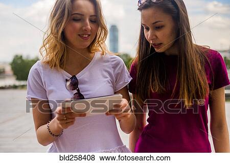 Caucasian women using digital tablet outdoors View Large Photo Image Stock Photo - Caucasian women using digital tablet outdoors. Fotosearch