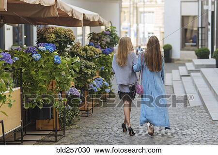 Caucasian women walking arm in arm in cobblestone street View Large Photo Image Stock Image - Caucasian women walking arm in arm in cobblestone street. Fotosearch