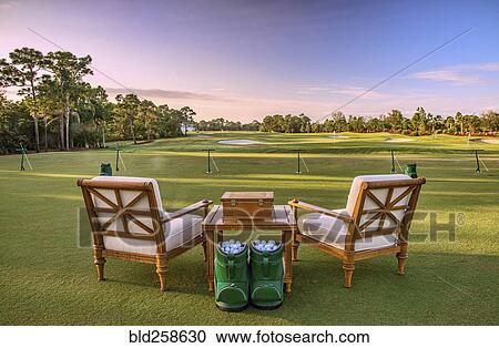 Stock Image - Chairs and golf balls on driving range. Fotosearch