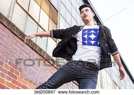 Chinese man jumping near red brick wall View Large Photo Image Stock Photo - Chinese man jumping near red brick wall. Fotosearch