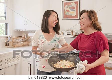 Stock Image - Chinese mother and daughter cooking together. Fotosearch