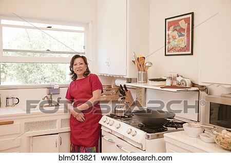 Stock Image - Chinese woman cooking in kitchen. Fotosearch
