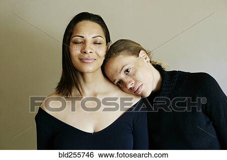Stock Photograph - Close up of affectionate mixed race women wearing sweaters. Fotosearch