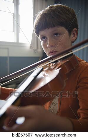 Stock Photo - Close up of Caucasian boy 1acticing violin. Fotosearch