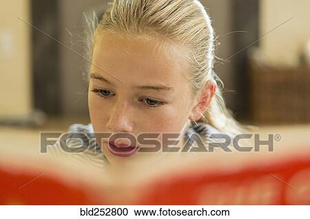 Stock Image - Close up of Caucasian girl reading book. Fotosearch