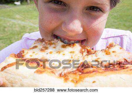 Close up of Caucasian girl with braces biting pizza View Large Photo Image Stock Photo - Close up of Caucasian girl with braces biting pizza. Fotosearch