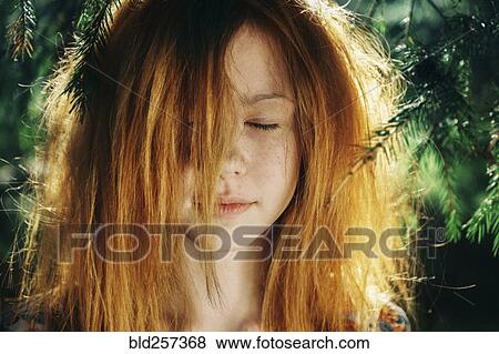 Stock Photo - Close up of Caucasian teenage girl near pine tree. Fotosearch