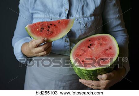 Stock Image - Close up of Caucasian woman holding slice of watermelon. Fotosearch