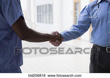 Stock Photo - Close up of doctor and nurse shaking hands. Fotosearch