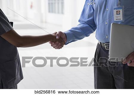 Stock Photograph - Close up of doctor and nurse shaking hands. Fotosearch