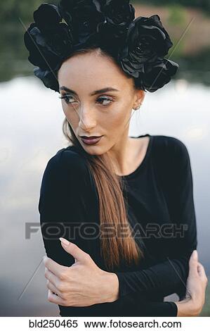Stock Photography - Close up of Middle Eastern woman wearing black dress near lake. Fotosearch
