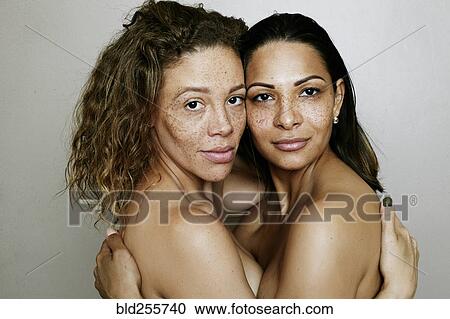 Stock Image - Close up of mixed race women hugging. Fotosearch