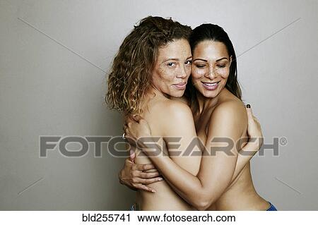 Stock Image - Close up of mixed race women hugging. Fotosearch