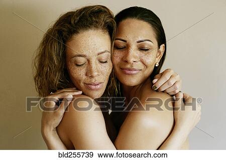 Stock Photo - Close up of mixed race women hugging. Fotosearch