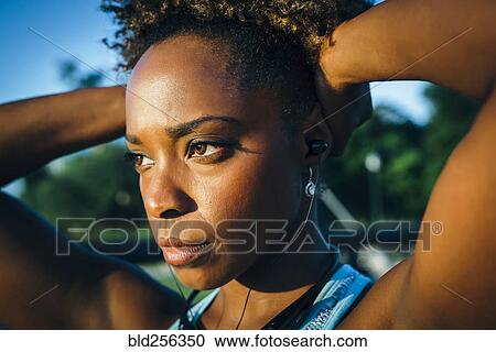 Stock Image - Close up of serious mixed race woman listening to earbuds. Fotosearch