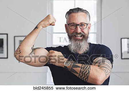 Stock Photography - Close up of smiling muscular Caucasian hipster man flexing biceps. Fotosearch