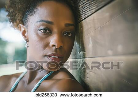 Stock Image - Close up portrait of serious mixed race woman leaning on wall. Fotosearch