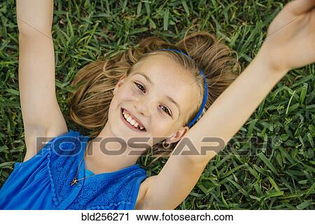 Close up portrait of smiling Caucasian girl laying on grass View Large Photo Image Stock Image - Close up portrait of smiling Caucasian girl laying on grass. Fotosearch