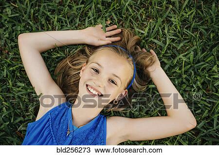 Close up portrait of smiling Caucasian girl laying on grass View Large Photo Image Stock Image - Close up portrait of smiling Caucasian girl laying on grass. Fotosearch