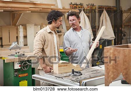 Stock Photo - Co-workers woodworking in workshop. Fotosearch