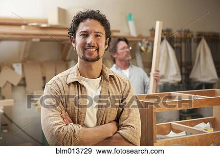 Stock Photo - Co-workers woodworking in workshop. Fotosearch