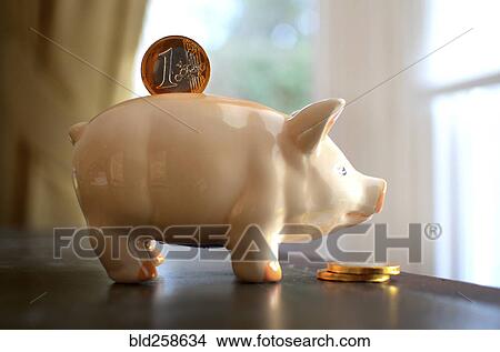 Picture - Coin in slot of piggy bank. Fotosearch