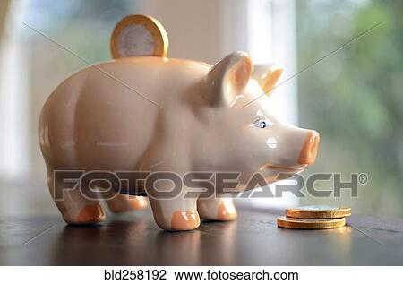 Stock Image - Coin in slot of piggy bank. Fotosearch