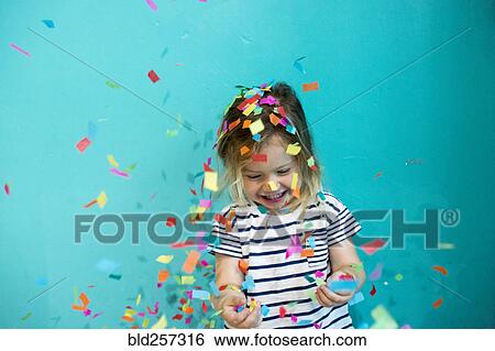 Stock Photograph - Colorful confetti falling on Caucasian girl. Fotosearch