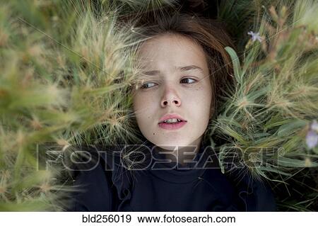 Stock Photo - Concerned Caucasian girl laying in field. Fotosearch