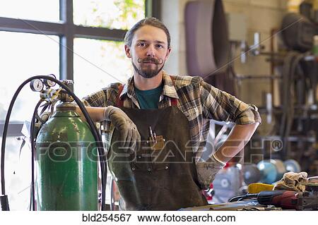 Confident Caucasian man leaning on gas tank in workshop View Large Photo Image Stock Photo - Confident Caucasian man leaning on gas tank in workshop. Fotosearch