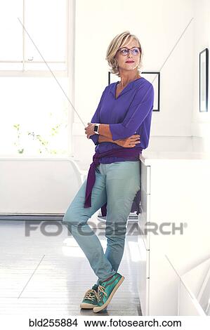 Picture - Confident Caucasian woman leaning on cabinet. Fotosearch