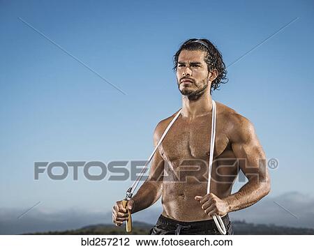 Stock Image - Confident Hispanic man holding jump rope. Fotosearch