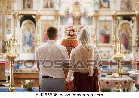 Stock Photograph - Couple and priest standing in church. Fotosearch
