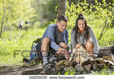 Stock Image - Couple building campfire in the woods. Fotosearch