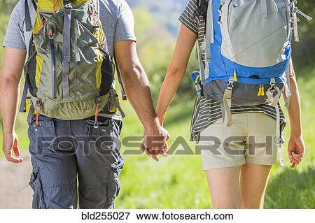 Stock Photo - Couple carrying backpacks and holding hands. Fotosearch