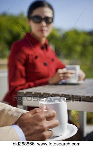 Stock Photograph - Couple drinking coffee outdoors. Fotosearch