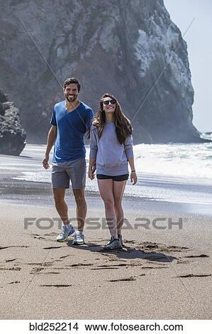 Couple holding hands and walking on beach View Large Photo Image Picture - Couple holding hands and walking on beach. Fotosearch