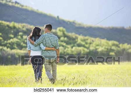 Stock Image - Couple hugging and walking near mountain. Fotosearch